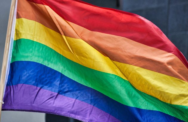 Bandeira arco-íris do orgulho LGBTQIA+ tremulando ao vento, exibindo cores vibrantes.
