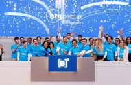 Equipe BTG Pactual DEBB11 celebra lançamento na B3. Pessoas em camisetas azuis, mãos para o alto, confetes voando.