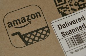 Caixa de papelão Amazon com logotipo e etiqueta de entrega "Delivered Scanned" e código de barras.