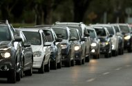 Longa fila de carros em engarrafamento. Motorista entediado visível ao volante de um carro.