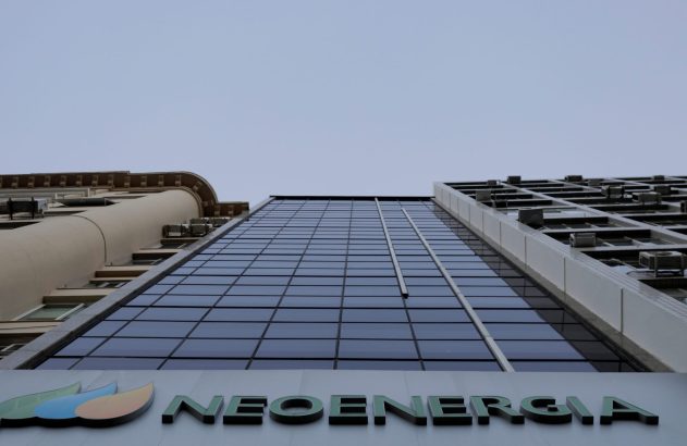 Fachada de prédio com painéis de vidro e letreiro "NEOENERGIA" em destaque. Vista de baixo.