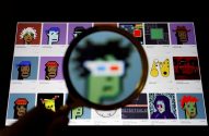 Mão segurando lupa sobre tela com NFTs, como CryptoPunks, focando um deles.