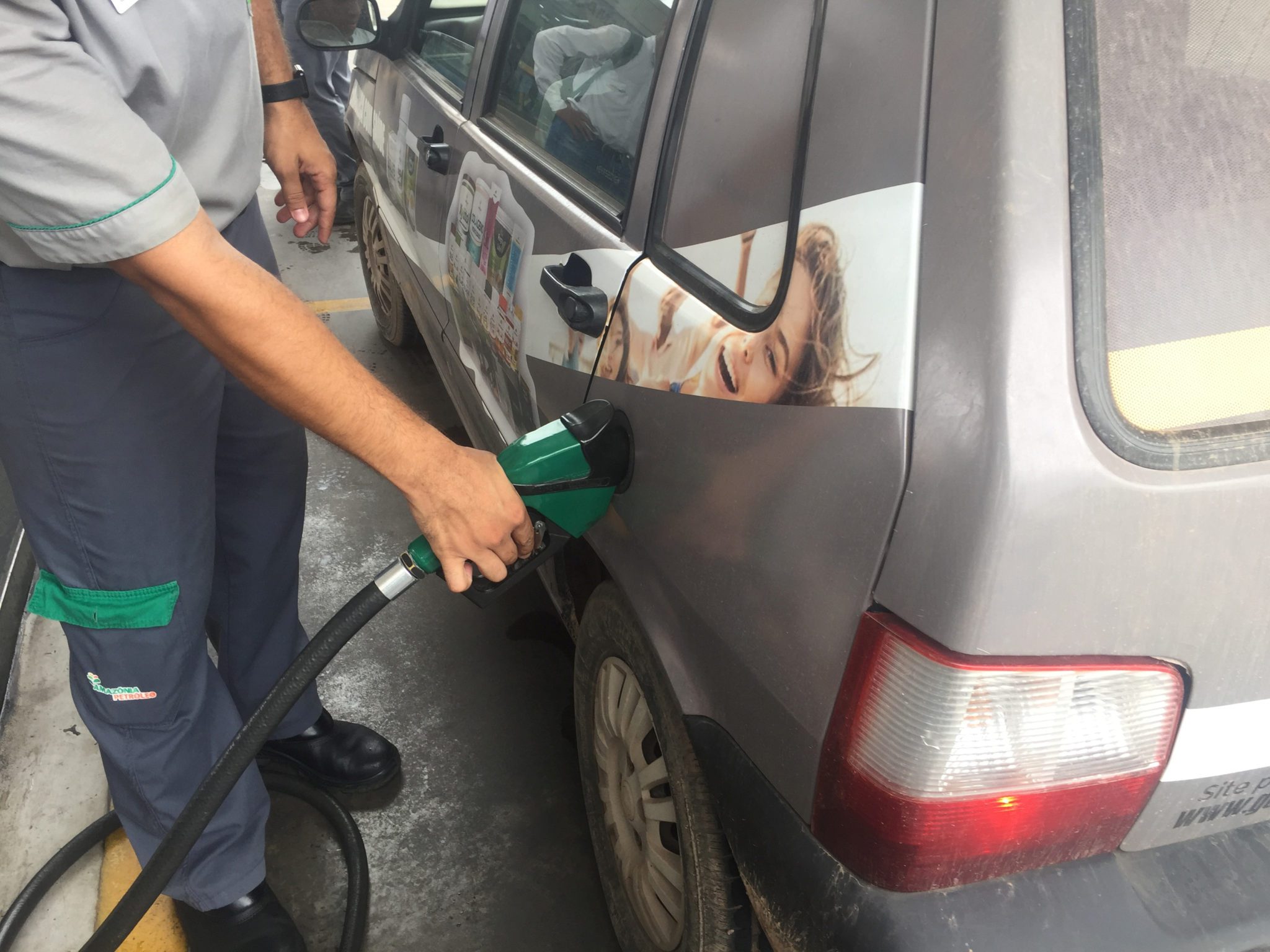 Frentista abastece veículo em posto