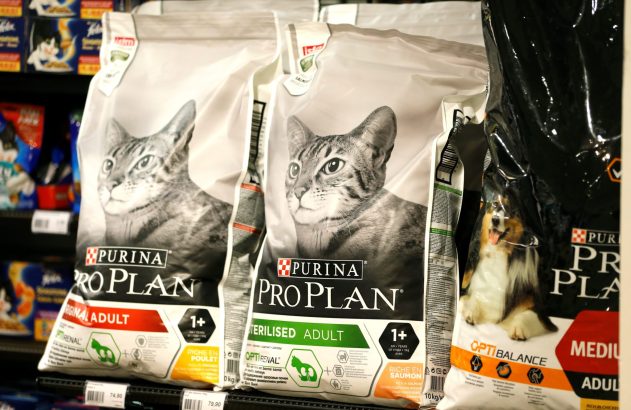 Sacos de ração Purina Pro Plan para gatos e cães em prateleira de loja, com preços visíveis.