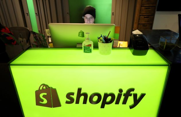 Pessoa trabalhando em mesa verde iluminada com logo Shopify.