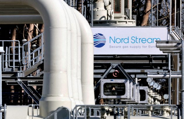 Tubulação de gás Nord Stream: grandes tubos brancos e letreiro azul com o logotipo "Nord Stream" em instalação industrial.