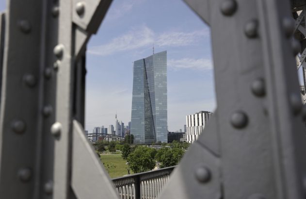 Edifício moderno de vidro e aço ao centro, com skyline ao fundo, enquadrado por estrutura metálica cinza com rebites.