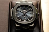 Um relógio Patek Philippe com mostrador escuro, dia, mês e fases da lua. Em expositor.