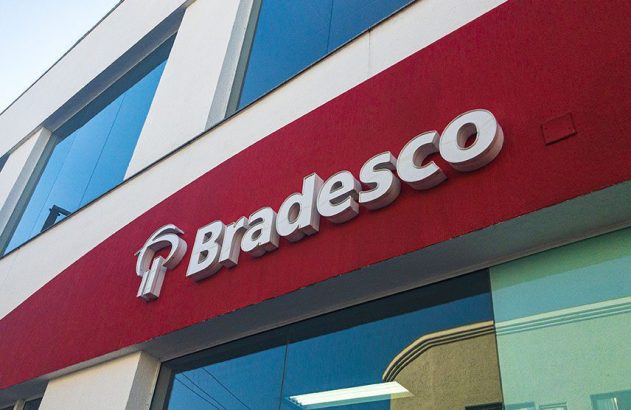 Prédio moderno com grande letreiro vermelho do Bradesco em letras 3D brancas e janelas espelhadas.