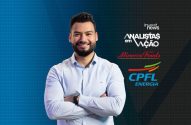 Um homem sorridente de barba, camisa azul e braços cruzados. Fundo com logos de empresas.