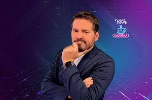 Homem pensativo, barba, terno escuro, mão no queixo. Fundo tecnológico azul/roxo com logo 'Invest News Cafeína'.