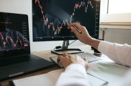 Homem aponta para tela de computador com gráfico de ativos