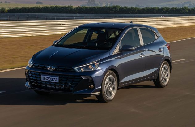 Hatchback Hyundai HB20 azul escuro em movimento em pista de testes, com rodas borradas pela velocidade.