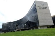 Edifício moderno do Tribunal Superior do Trabalho com fachada curva de vidro escuro e lateral de concreto.