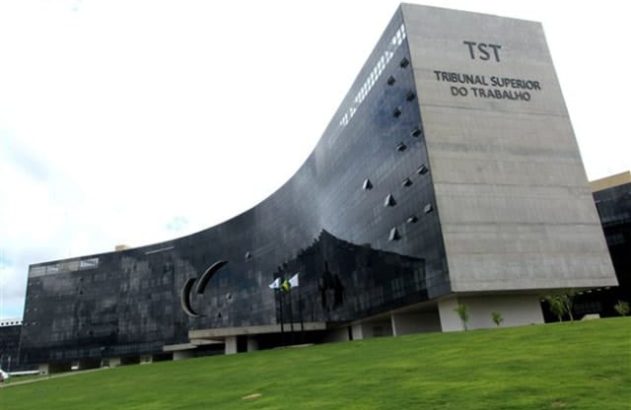 Edifício moderno do Tribunal Superior do Trabalho com fachada curva de vidro escuro e lateral de concreto.