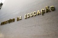 Letras douradas "MINISTÉRIO DA EDUCAÇÃO" em parede de edifício.