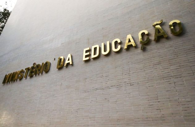 Letras douradas "MINISTÉRIO DA EDUCAÇÃO" em parede de edifício.