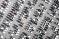 Vista aérea de um vasto estacionamento com centenas de carros alinhados perfeitamente em fileiras.