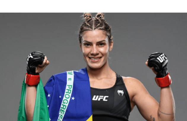 Lutadora de MMA sorrindo, flexionando bíceps com luvas e bandeira do Brasil.