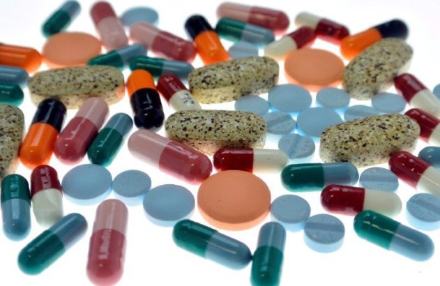 Pílulas e cápsulas multicoloridas de variados tamanhos e formas em fundo branco.