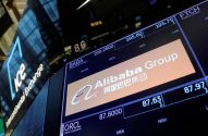 Telas digitais exibem informações da bolsa de valores, com destaque para a ação da Alibaba Group.