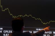 Pessoa aponta para tela com gráfico de ações e dados financeiros.