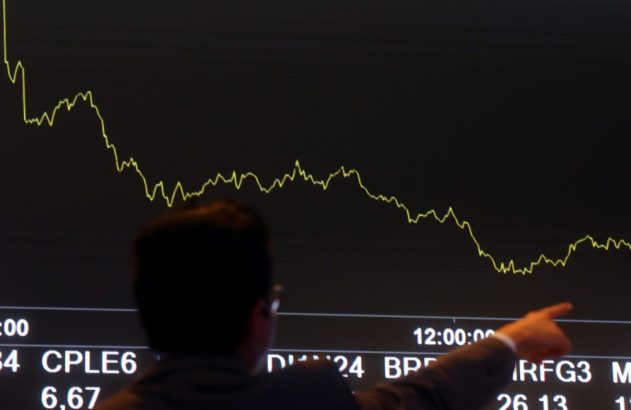 Pessoa aponta para tela com gráfico de ações e dados financeiros.