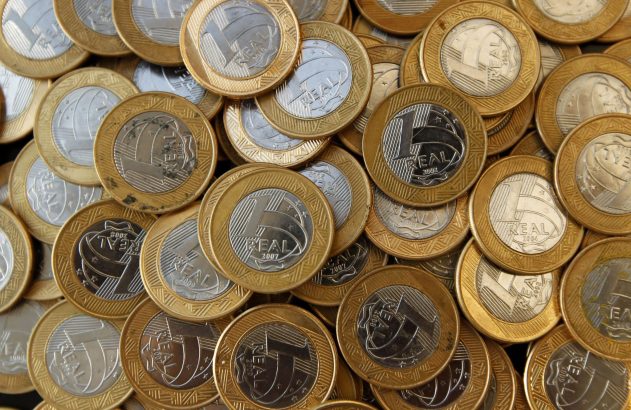 Moedas bimetálicas de 1 Real brasileiro vistas de cima, mostrando 'REAL' e diversos anos.