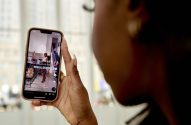 Mão de pessoa segurando celular. Na tela, vídeo "23 YEAR OLD BLACK GIRL WORKING ON WALL STREET".