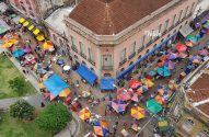 Vista aérea de um vibrante mercado de rua com guarda-chuvas coloridos e pessoas.