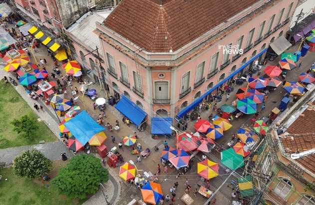 Vista aérea de um vibrante mercado de rua com guarda-chuvas coloridos e pessoas.