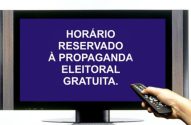 TV exibe mensagem de horário eleitoral gratuito, com mão segurando controle remoto.