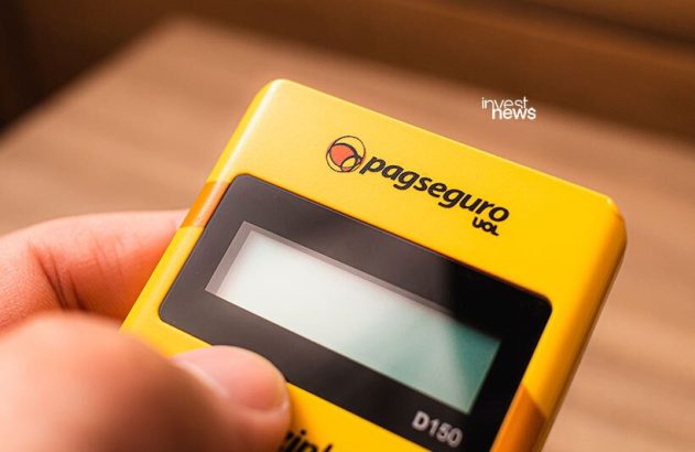 Mão segura máquina de cartão PagSeguro D150 amarela.
