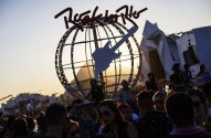 Multidão em festival Rock in Rio ao pôr do sol, com o símbolo de globo e guitarra em destaque.