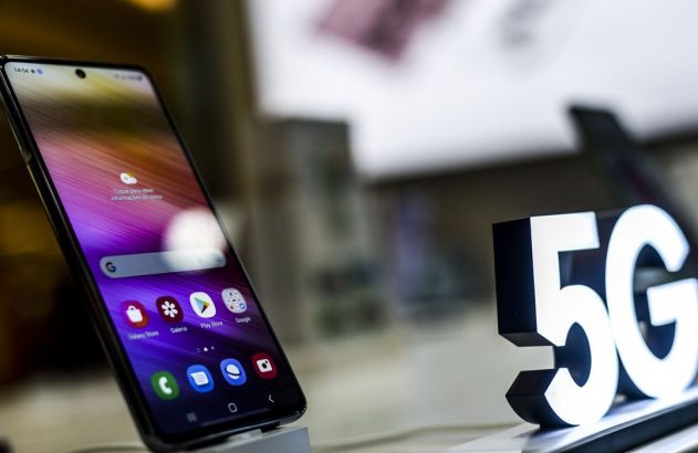 Celular exibindo tela com aplicativos e letreiro "5G" luminoso em destaque.