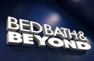 Letreiro branco e iluminado "Bed Bath & Beyond" em parede azul escura.