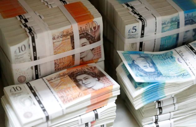 Pilhas de notas de libras esterlinas de £5 e £10, empacotadas com faixas, mostrando a Rainha Elizabeth II.