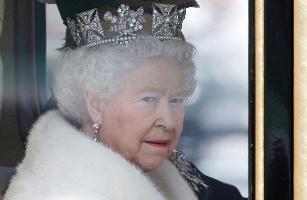 Close-up da Rainha Elizabeth II, coroa de diamantes e pérolas, casaco de pele branca, olhando à direita através de janela.