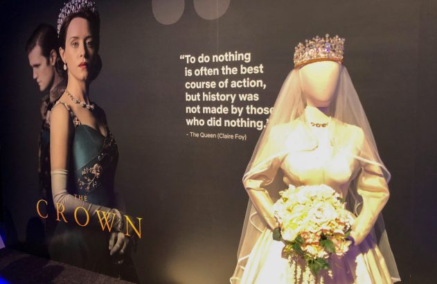 Exposição de "The Crown" com pôster da Rainha Elizabeth II (Claire Foy) e manequim vestindo o traje de noiva.