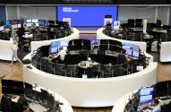 Corretores trabalham na movimentada Bolsa de Frankfurt, monitores exibem dados do mercado.