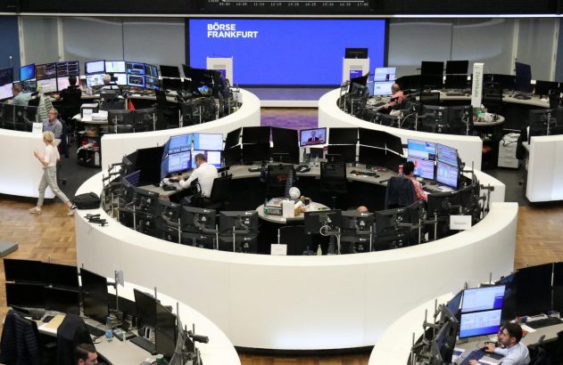 Corretores trabalham na movimentada Bolsa de Frankfurt, monitores exibem dados do mercado.