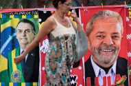 Mulher borrada passa por faixas eleitorais de Bolsonaro e Lula penduradas.