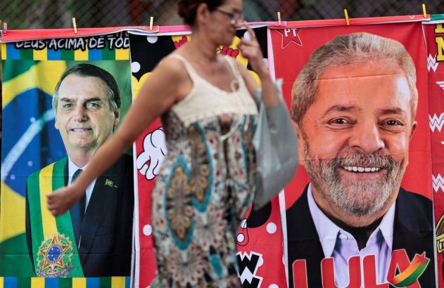Mulher borrada passa por faixas eleitorais de Bolsonaro e Lula penduradas.