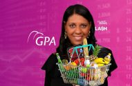 tatiana santiago, apresentadora do investnews, com as mãos estendidas segurando uma cesta de alimentos e ao fundo o logo do GPA