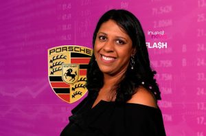 Mulher sorridente apresenta notícias de mercado com logo Porsche e 'invest news FLASH' ao fundo.