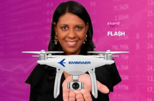 Mulher sorridente segura drone branco Embraer em fundo rosa com dados financeiros e "invest news".