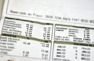 Detalhe de fatura de energia elétrica mostrando tarifas, impostos e histórico de consumo.