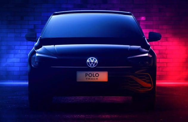 Carro escuro, modelo Polo Track, com logo VW, iluminado por luzes neon azul e vermelho, contra parede de tijolos.