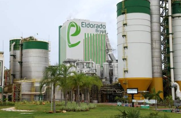 Fábrica Eldorado Brasil: vista externa de silos altos, prédio principal e paisagem verde com palmeiras.