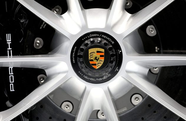 Close-up de roda Porsche com cubo centerlock, logotipo da marca e texto para remoção/aperto.